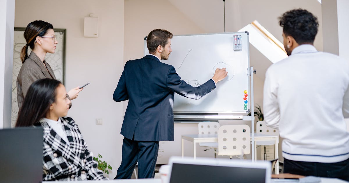 A diverse team standing at a whiteboard during a collaborative planning and prototyping session