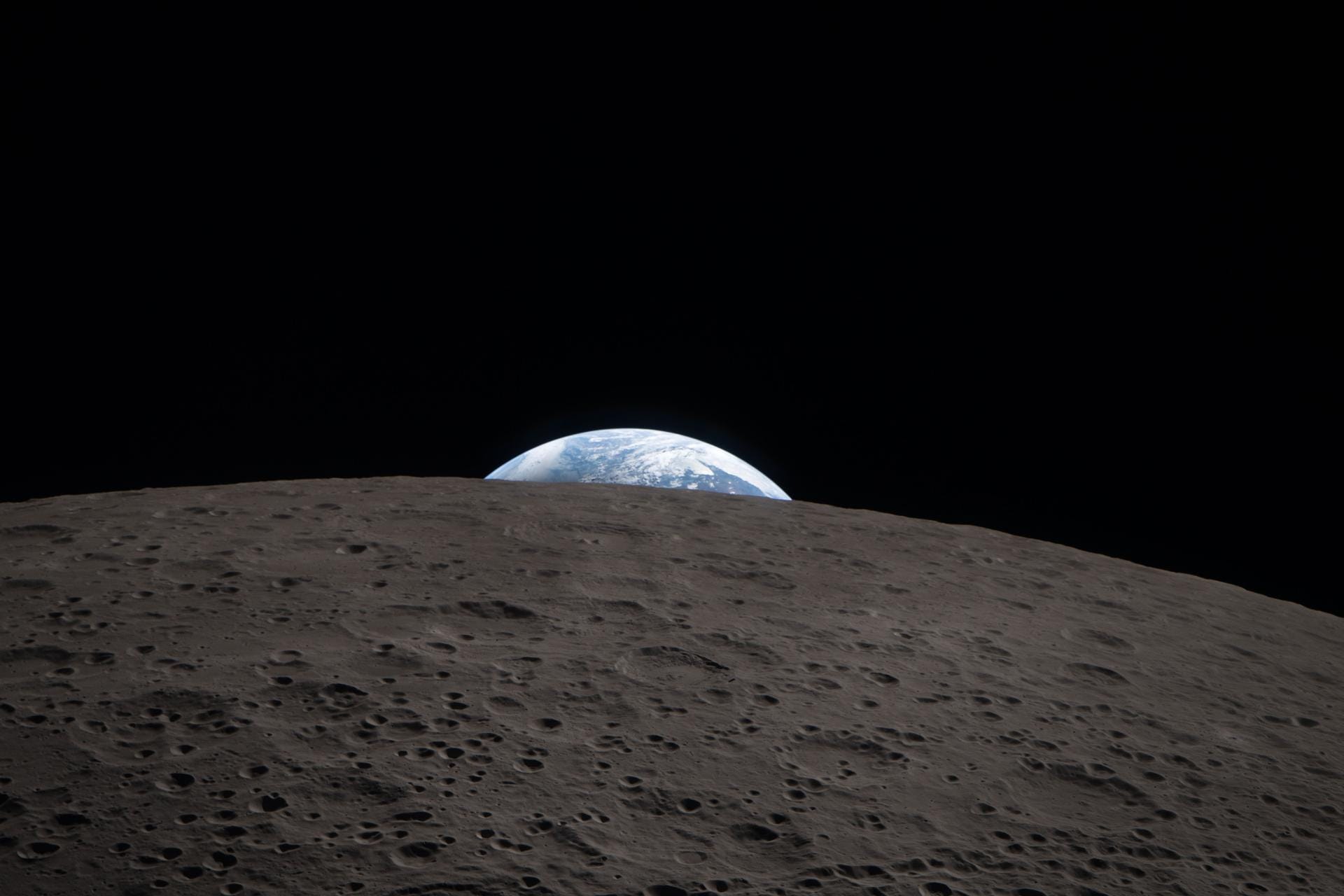 Earth rising above the lunar surface during the Artemis II far-side flyby, an Artemis-era echo of the 1968 Apollo 8 Earthrise photograph